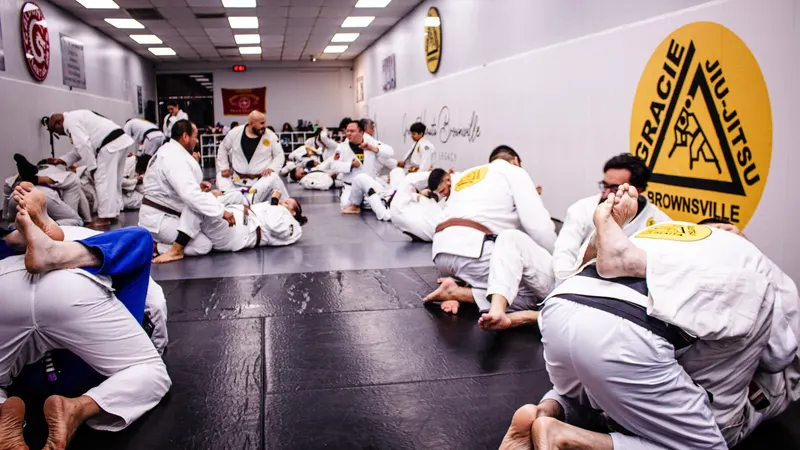 Students drilling jiu-jitsu techniques in pairs on the mat under the Gracie Jiu-Jitsu Brownsville crest