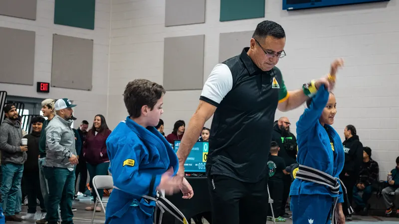 A referee raises a young competitor's hand after a kids jiu-jitsu match at the RGV Open tournament in McAllen